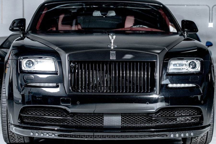 Luxury black sedan with prominent grille and distinctive emblem in a modern car showroom