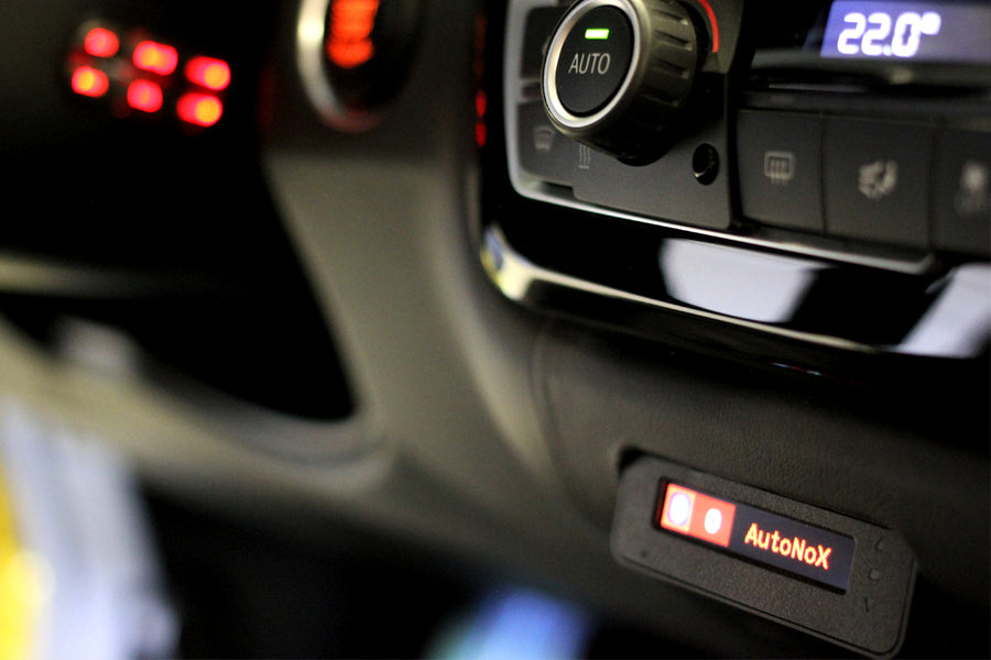 Close-up of a car's dashboard with AutoNox device and illuminated control buttons
